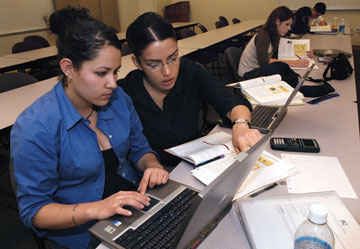 photo - two latina CMC students work at a computer