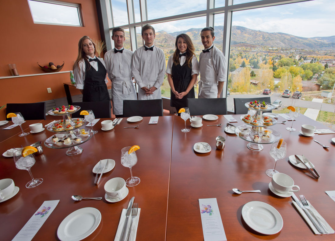 photo: Rest Management students stand behind a table set for a high tea.