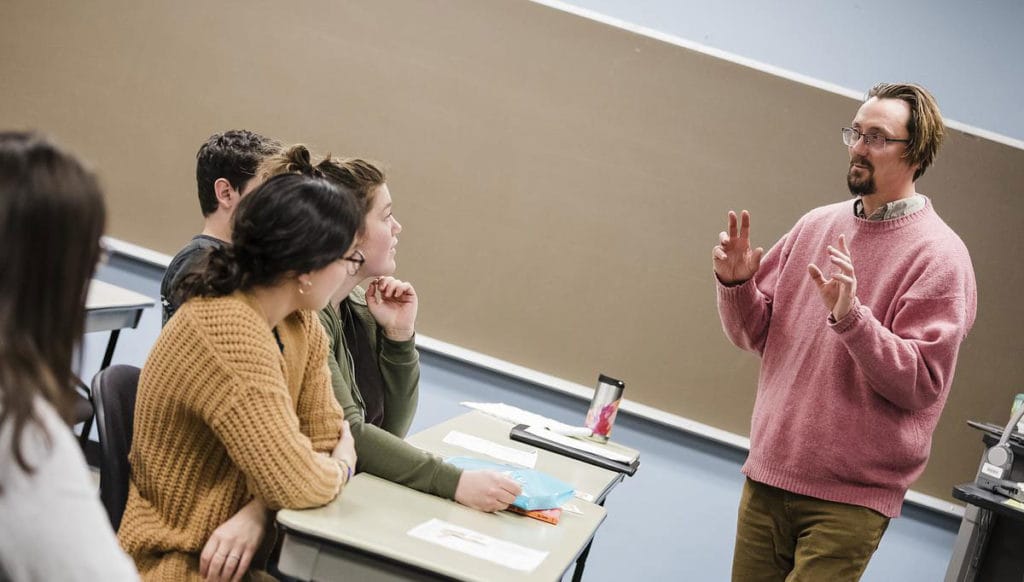 CMC professor talks to students in a classroom.