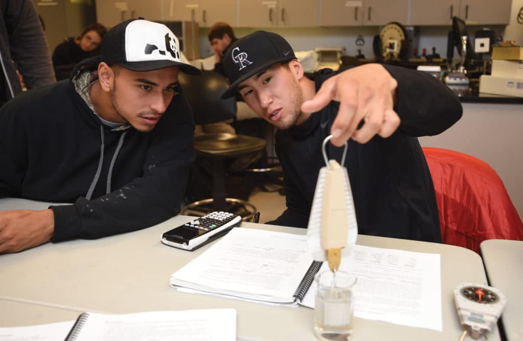 Two CMC students work closely together in a physics class.