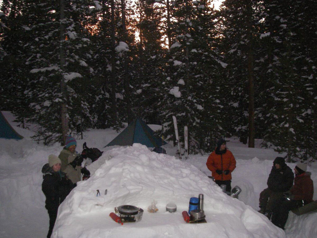 CMC Outdoor Recreation Leadership students prepare meals outside their snow cave shelter.