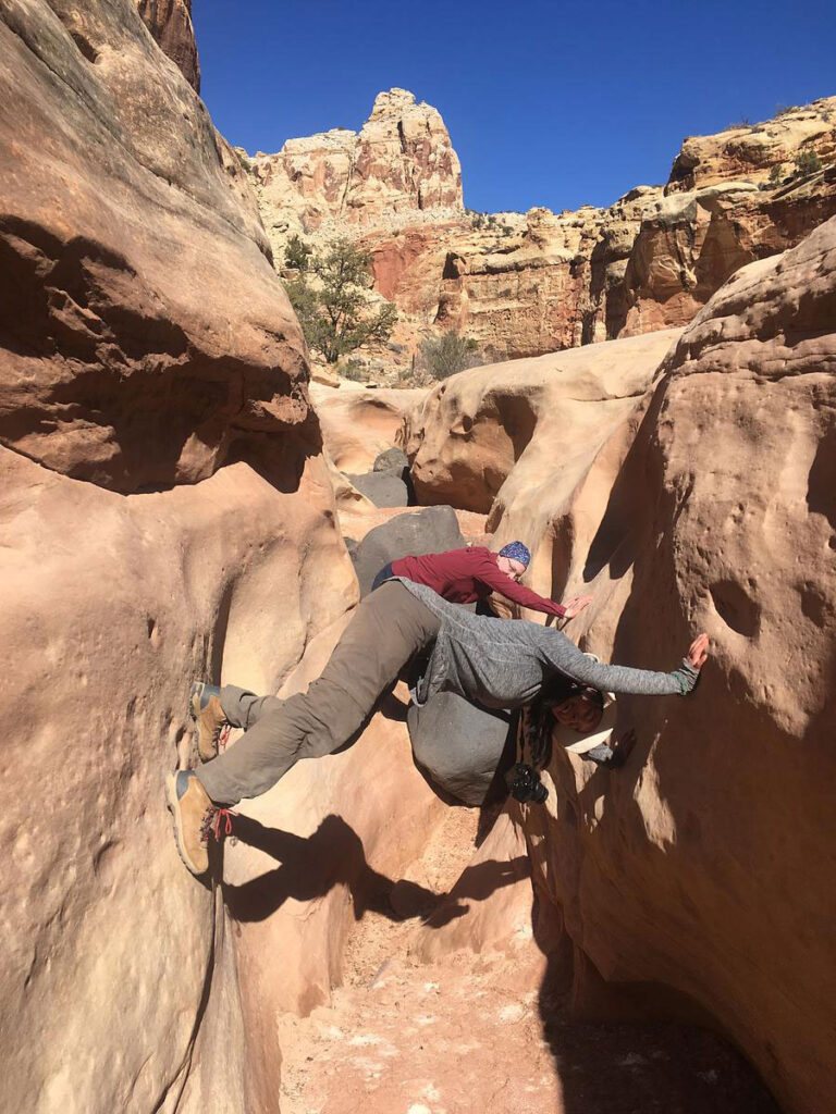 CMC Outdoor Education students climb in narrow canyon using a bridge technique during a desert orientation trip.