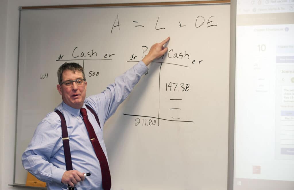 CMC Accounting instruction demonstrating in a classroom using a white board.